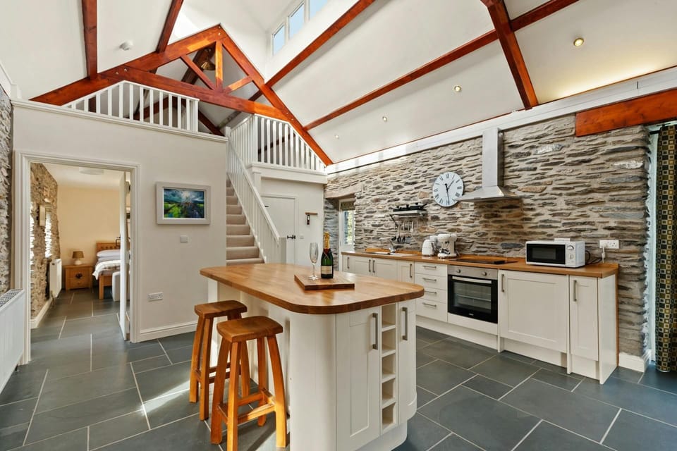 Kitchen Island and stools in the centre of the kitchen with oven, hob, microwave and kettle on units behind