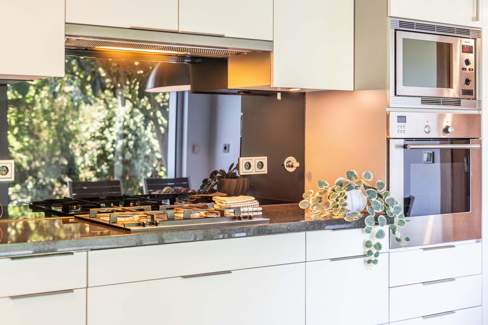 Modern kitchen with gas cooktop and mirrored backsplash — Villa Jasmine, luxury holiday villa in Herdade de Aroeira