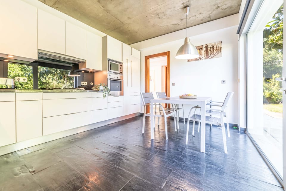 Modern open-plan kitchen and dining area with concrete ceiling — Villa Jasmine, holiday villa in Herdade de Aroeira