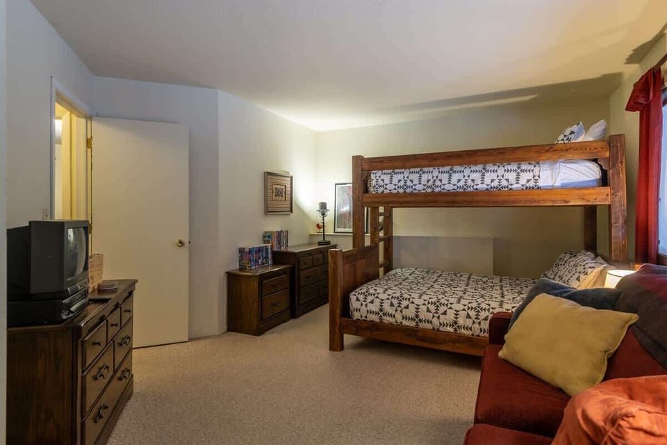 Lower level bedroom with a Pyramid bunk bed and sofa sleeper and exit door - TV is vintage with an old fashioned VHS to enjoy movies that are provided