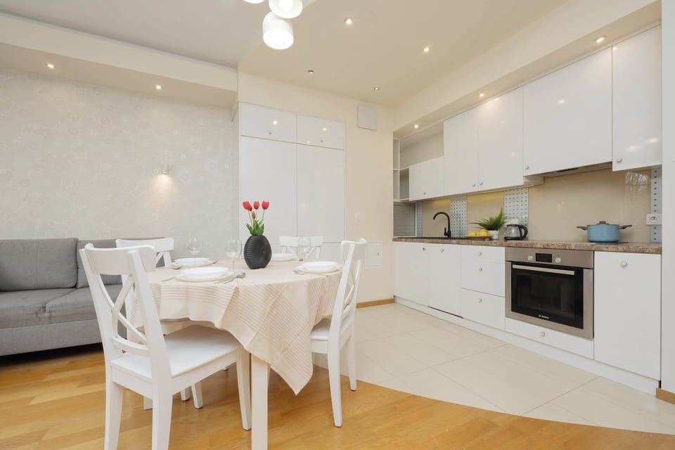 Modern white kitchen with built-in appliances and wooden flooring.