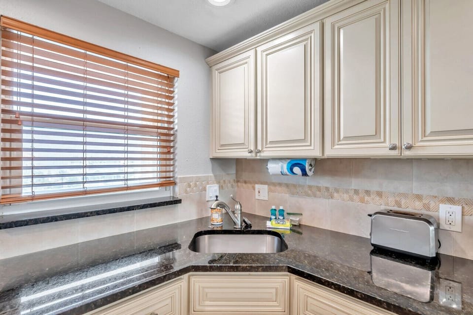 Sunlit kitchen corner w/ generous counter space and warm light filtering through the window.