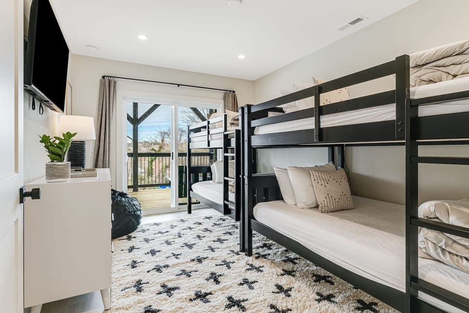 Corner view of Bedroom 5 downstairs with 4 twin bunk beds, large closet space, Smart Roku TV, and dresser