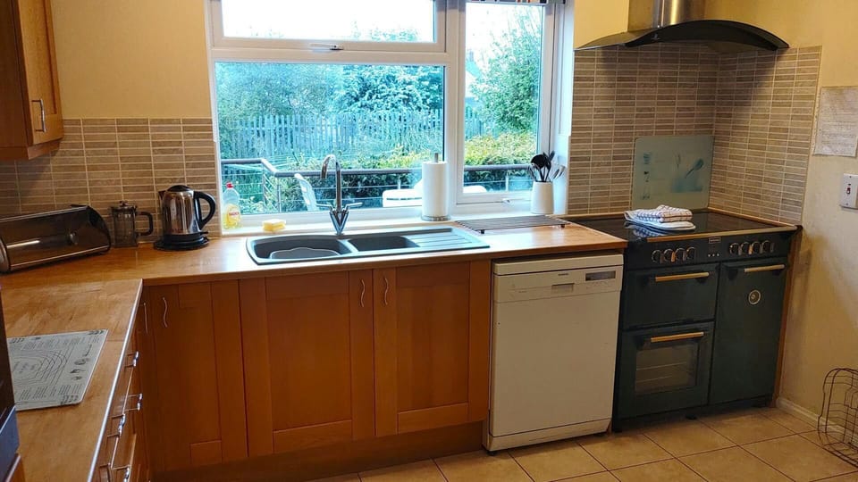 Spacious kitchen with dishwasher, electric part induction range cooker and kettle with extractor hood, built in microwave, fridge freezer, toaster