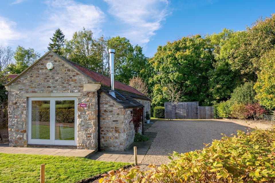 Exterior of Austin, a traditional stone holiday cottage with private entrance and gravel driveway in rural setting.