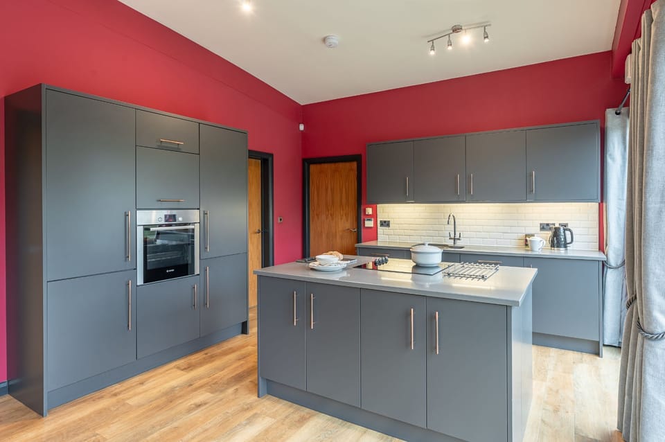 Kitchen at Isabella with a central island, built-in oven, and worktop with sink and appliances.