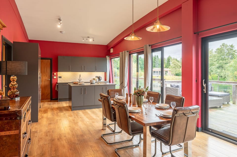 Dining and kitchen area at Isabella with a dining table, kitchen island, and doors opening onto the deck by the lake.