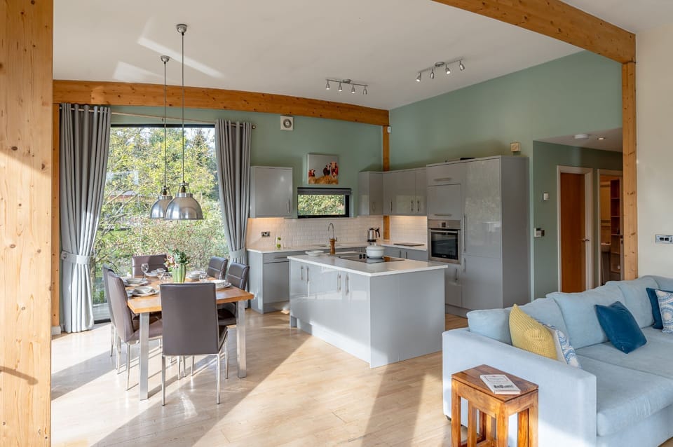 Kitchen and living area in Jasper lodge with sofas, armchairs, dining area and floor-to-ceiling windows.