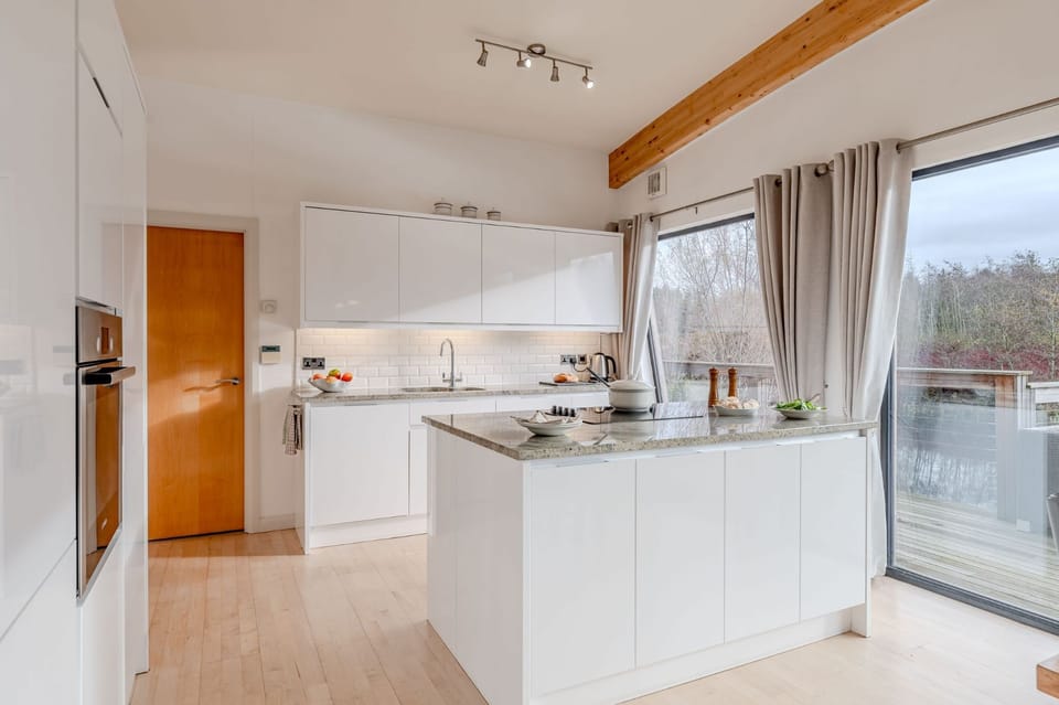 Modern fully equipped kitchen in Lulu lodge, Brompton Lakes with island unit  and lakeside views through large windows.