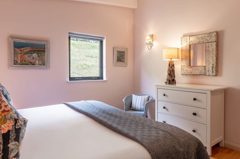 Spacious double bedroom with dresser, mirror and garden views in Iris lodge at Brompton Lakes.