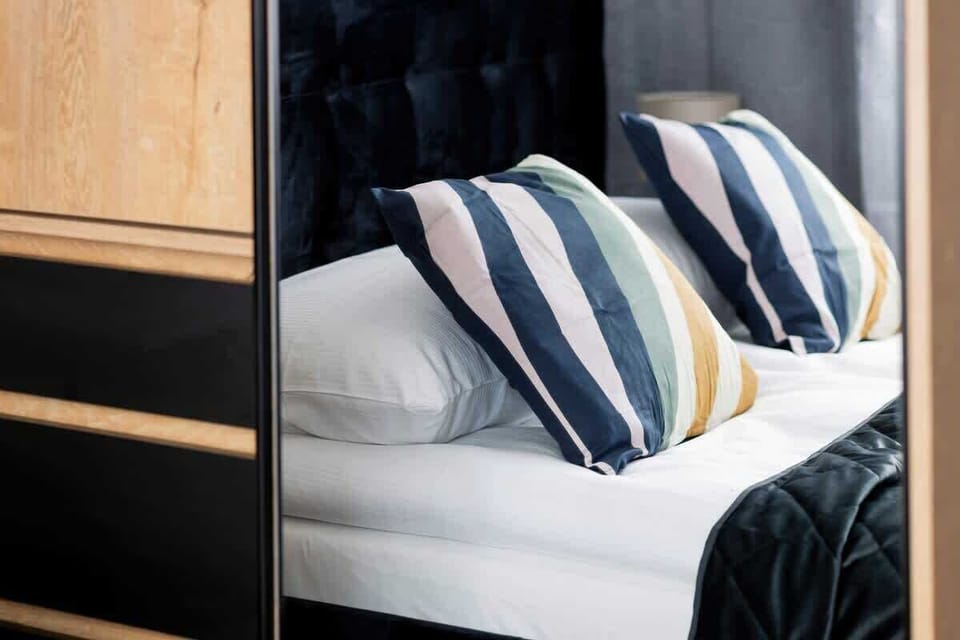Close-up of the bed with striped decorative pillows and bedside storage.