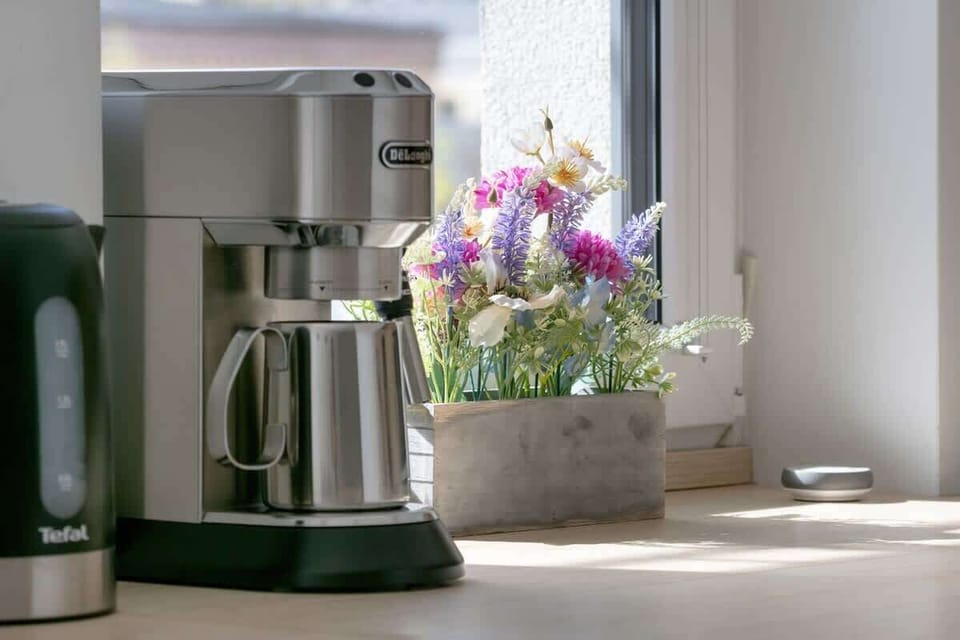 A close-up of a coffee station by the window, with a moka pot and fresh flowers adding a homely feel.