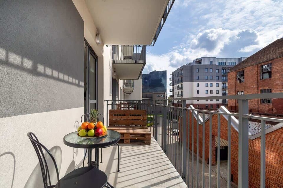 A well-furnished balcony with chairs and a table, offering a scenic city view and a relaxing outdoor space.