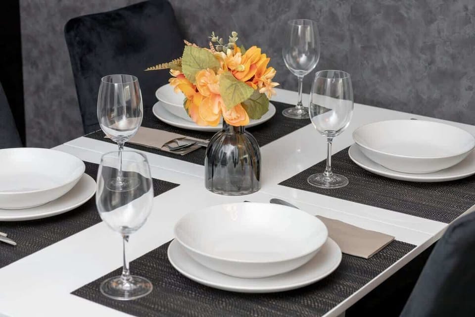 A beautifully arranged dining table with flowers, white plates, and wine glasses — ideal for entertaining.