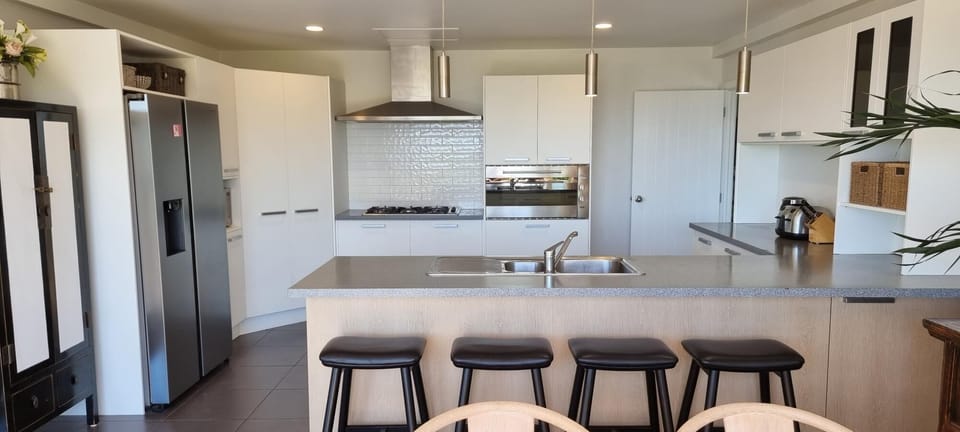 The modern well-equipped kitchen looks out over the dining area to the sea. 