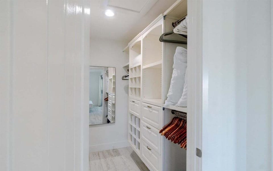 Spacious walk-in closet with custom shelving and ample storage for clothing and luggage.