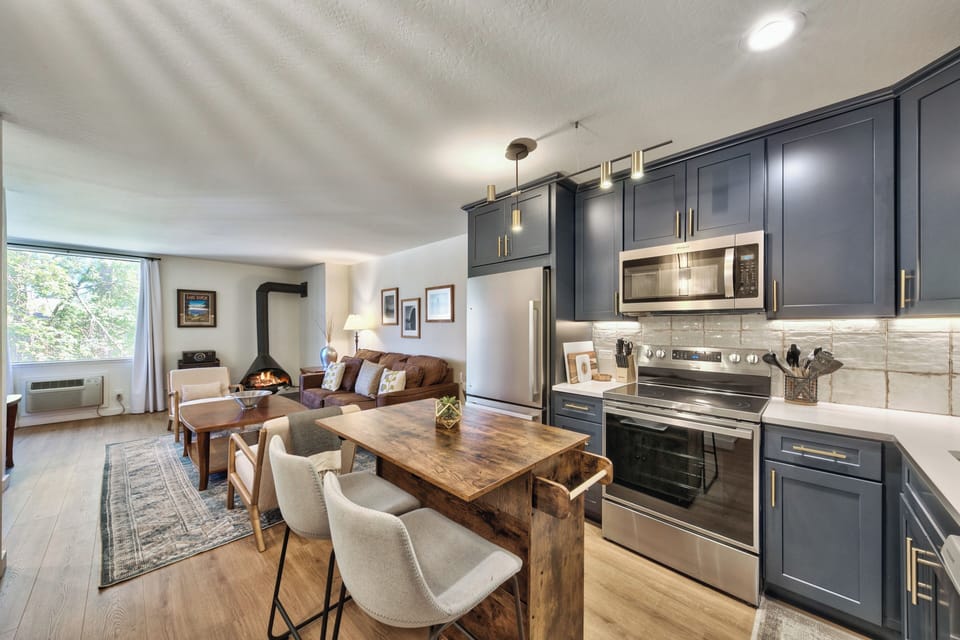 Your modern kitchen flows seamlessly into a cozy living space with fireplace, perfect for cooking memorable meals and relaxing after mountain adventures.