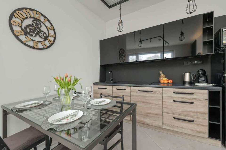 A modern kitchen with wooden cabinets and a black countertop. Includes a coffee maker and essentials for cooking.