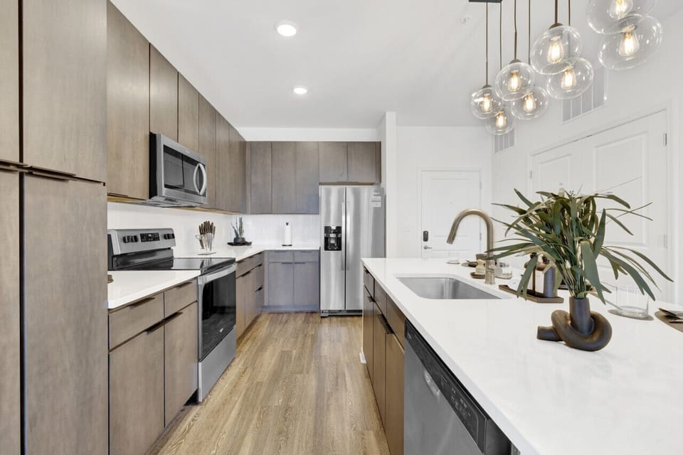 Modern kitchen with sleek stainless steel appliances and neatly arranged utensils, perfect for effortless cooking during your short-term rental stay.