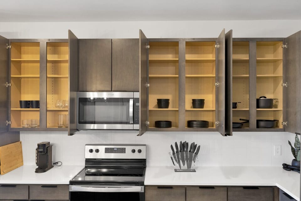 Modern kitchen with sleek stainless steel appliances and neatly arranged utensils, perfect for effortless cooking during your short-term rental stay.