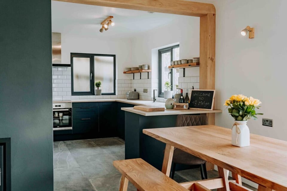 Ty Melyn No.2 Newgale – Stylish kitchen with wooden accents and a dining table set for six – complete with sea views from the window.