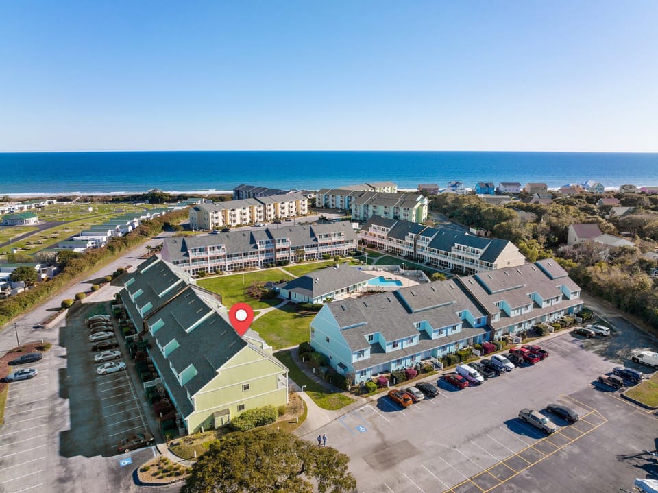 Aerial view of beachfront resort complex with multiple buildings, parking areas, and direct ocean access.