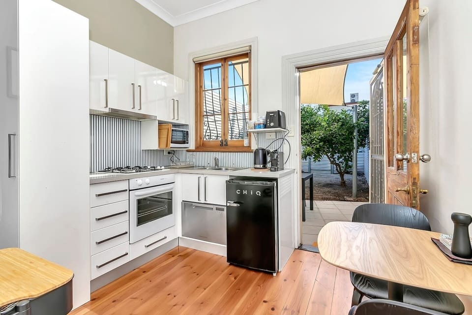 The charming compact kitchen corner has everything needed for home cooking such as a single-drawer dishwasher, oven, stovetop and range hood, mini fridge and a coffee machine. 
