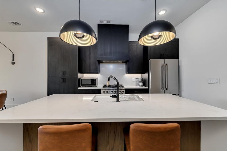Modern kitchen island w/ sleek pendant lighting & bar seating for casual dining