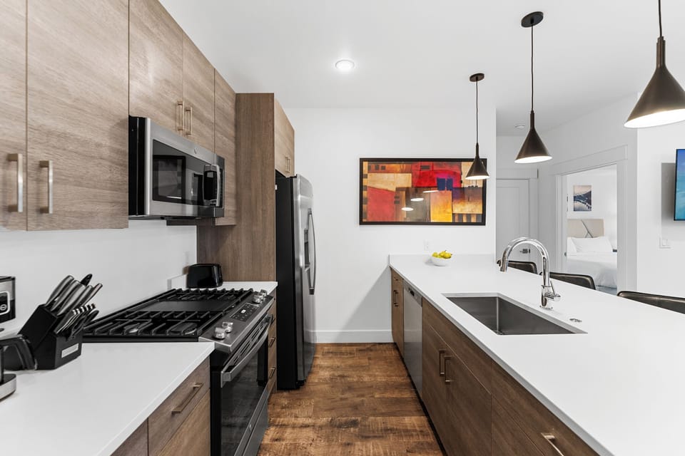 Your modern kitchen awaits with sleek appliances, warm wood cabinetry, and stylish pendant lighting perfect for cooking memorable meals.