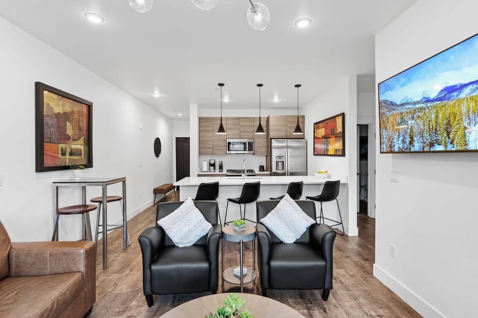 Relax in your stylish living space with modern black leather seating and a sleek open kitchen perfect for entertaining.
