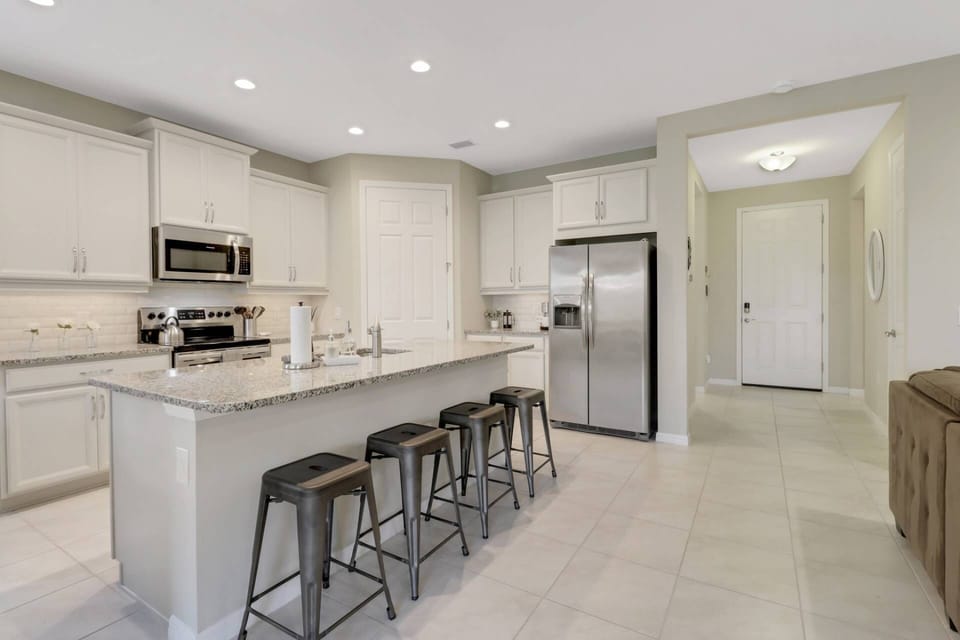 The well appointed kitchen has a granite island with barstool seating, full size stainless appliances and walk-in pantry