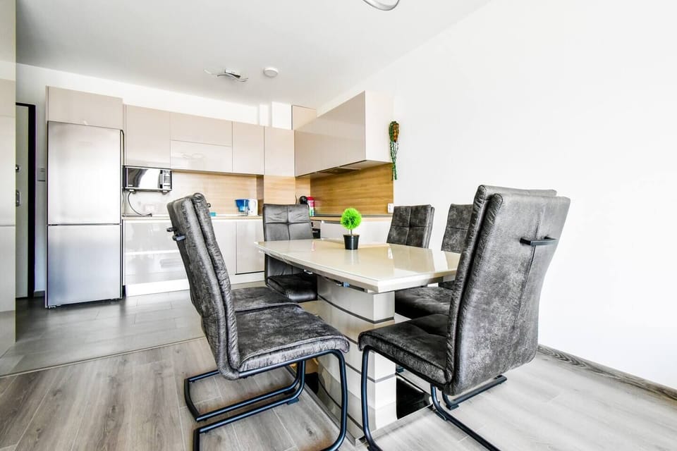 The dining area doubles as a productive workspace, with a sleek table at its center, surrounded by plush chairs that invite both comfortable dining and focused work sessions. The kitchen, with clean lines and modern appliances, stands ready for your culinary adventures or quick, efficient meal preparation. It's a space where functionality meets style, designed to complement your urban lifestyle.