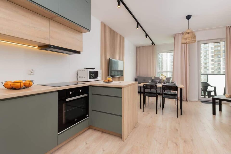 A wide view of the kitchen with grey cabinets, a microwave, and a sleek countertop, complemented by the dining area in the background.