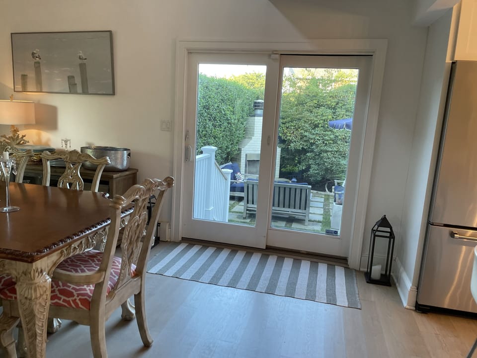 Indoor dining area walking out to side yard with fireplace, grill and couches 