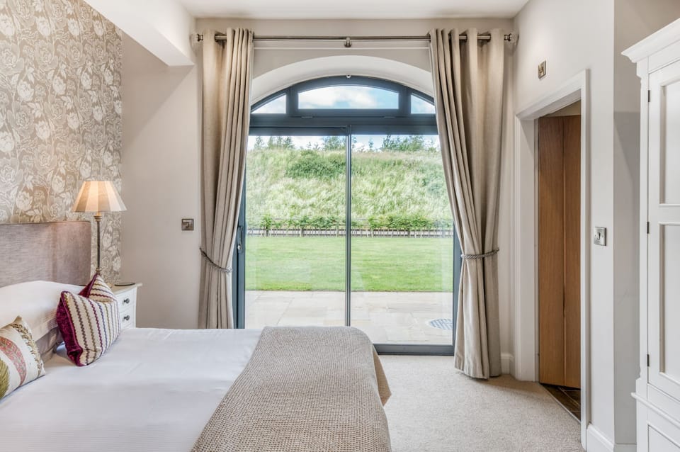 Light-filled bedroom at Dexter with patio doors opening onto the garden, creating a calm indoor-outdoor feel.