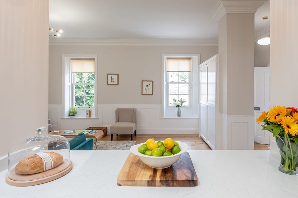 The Swaledale stylish kitchen island view with fresh flowers, fruit bowl and open-plan living beyond.