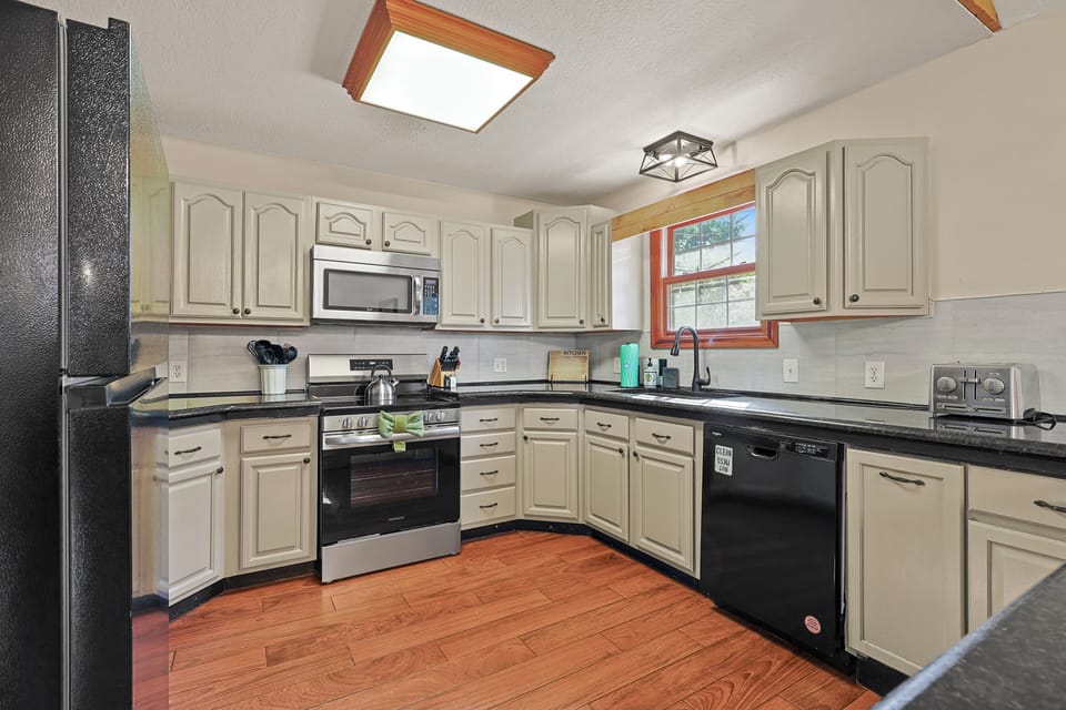 Bright kitchen featuring stainless steel appliances, generous counter space, dishwasher, microwave, and plenty of room for cooking and gathering.