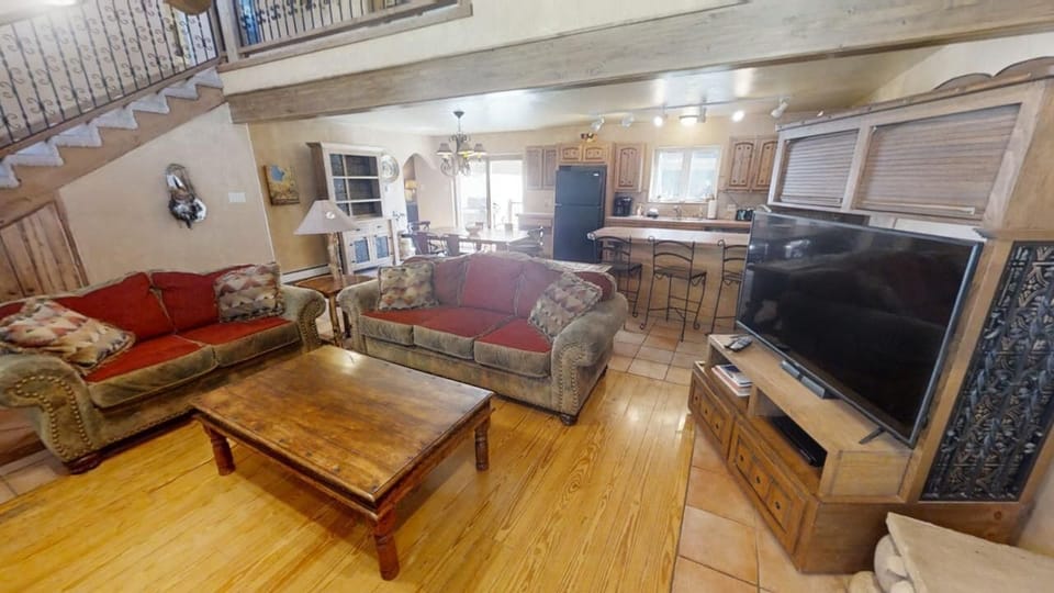 Your cozy open-concept retreat features a spacious living area with comfortable seating, large flat-screen TV, and a fully-equipped kitchen with breakfast bar—perfect for relaxing and enjoying meals together.