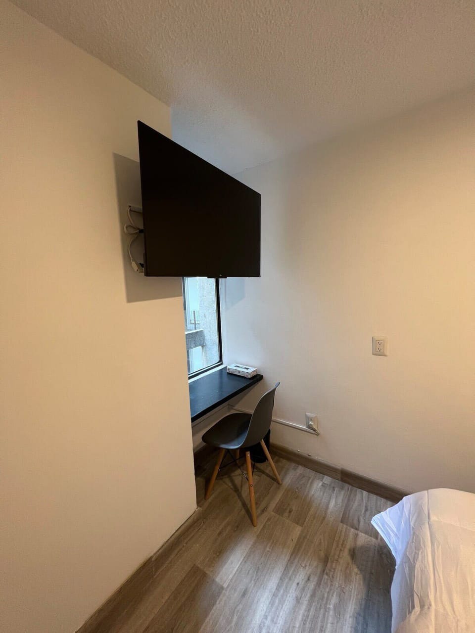 Wall-mounted TV for bedtime movies and desk area.