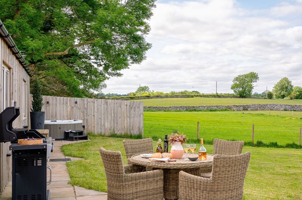 Bearskin patio seating area with wicker table and chairs on paving beside the timber-clad exterior.