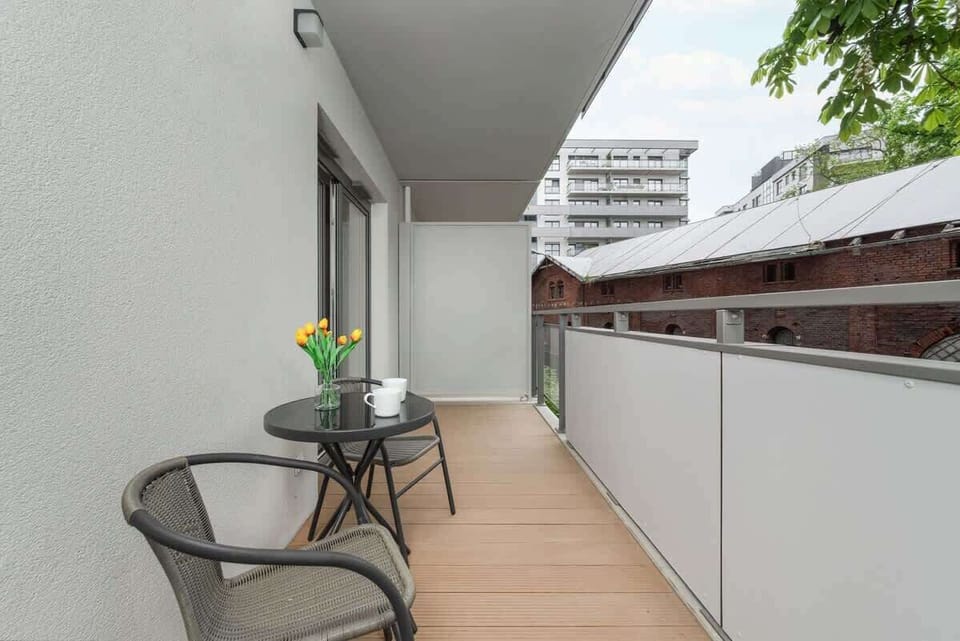 A balcony with wooden flooring, outdoor seating, and a city view. A peaceful place to unwind.