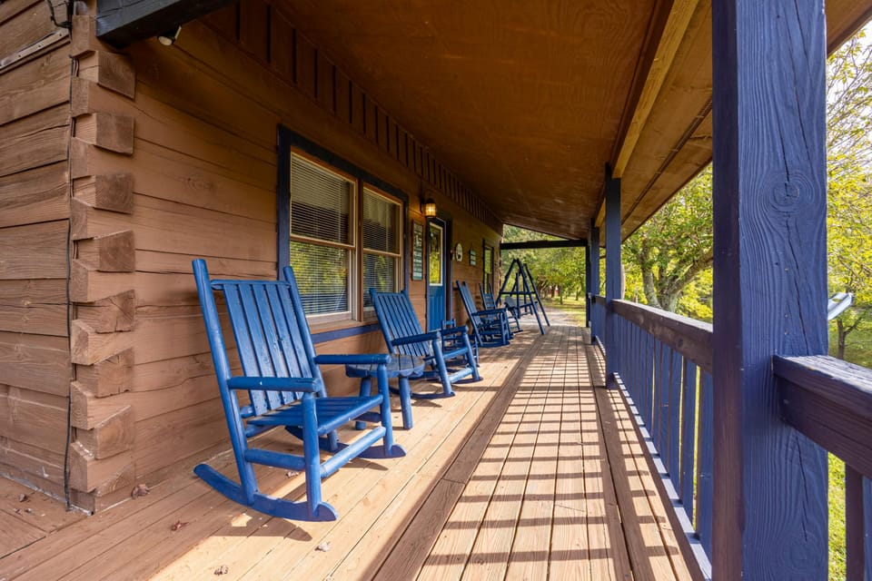 Settle into your favorite blue rocking chair on this welcoming covered porch, where dappled sunlight creates the perfect spot for morning coffee or evening relaxation.