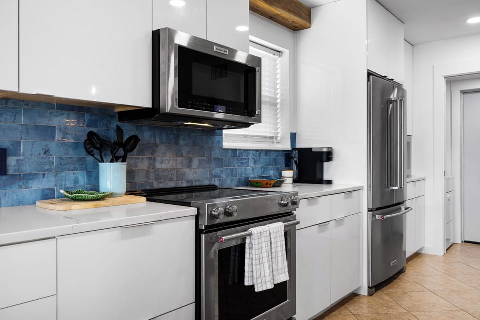 Fully equipped kitchen with stainless steel appliances and beautiful blue back splash