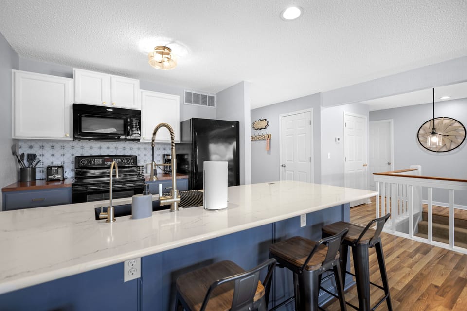 Modern kitchen with eat in bar and oven, dishwasher, microwave and refrigerator.