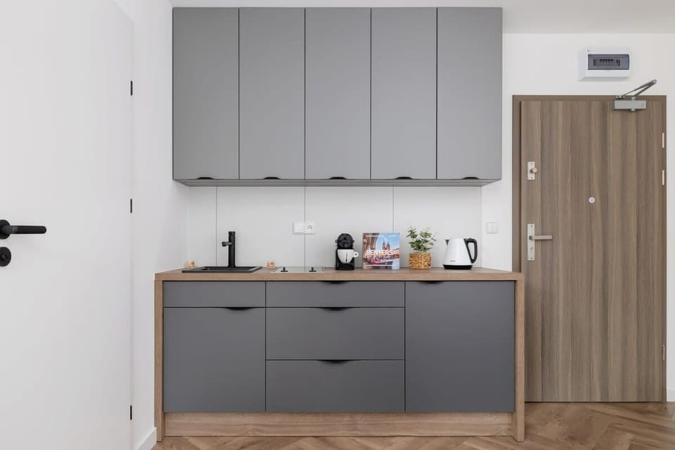 A simple kitchenette with grey cabinets, a microwave, and a wood accent wall.

