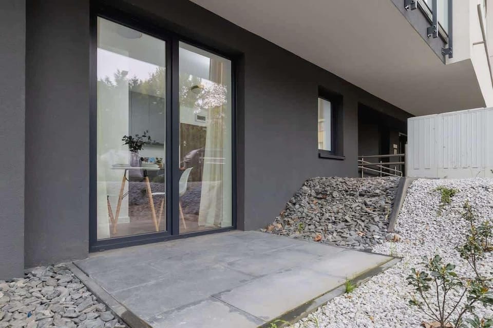 A private terrace exit with sliding glass doors, leading to a peaceful outdoor area with white stones.