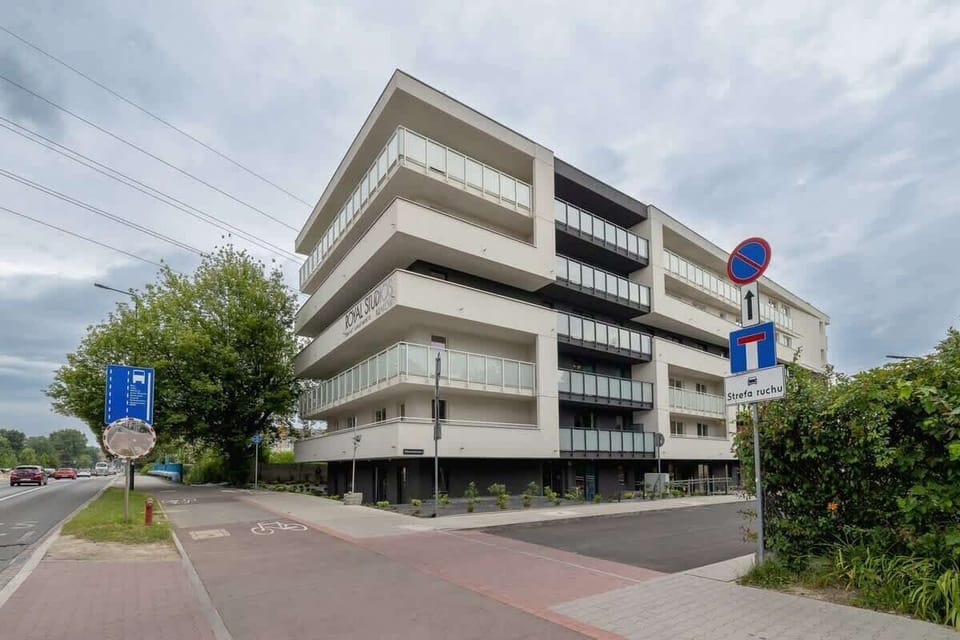 A city street corner view with a mid-rise modern apartment building and clean sidewalks.