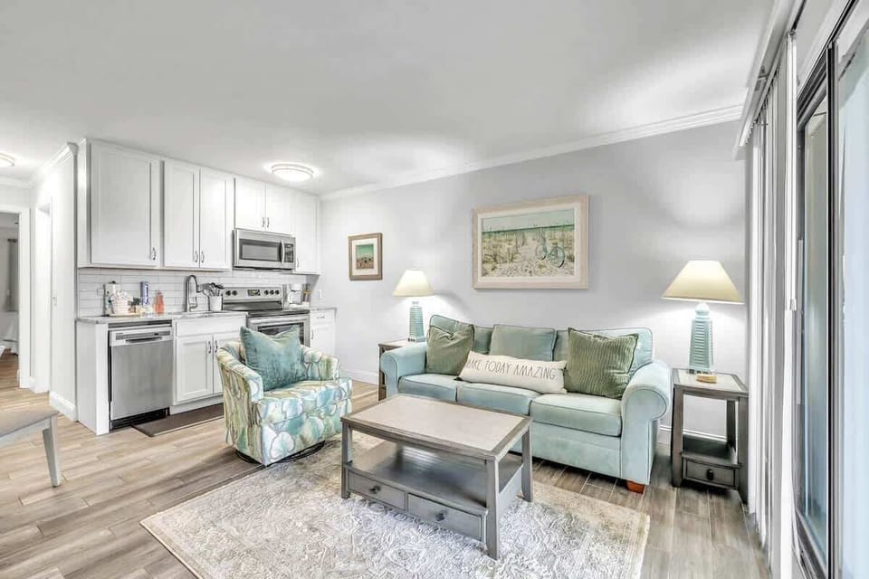 Bright living area with coastal-inspired decor and a fully equipped kitchen.