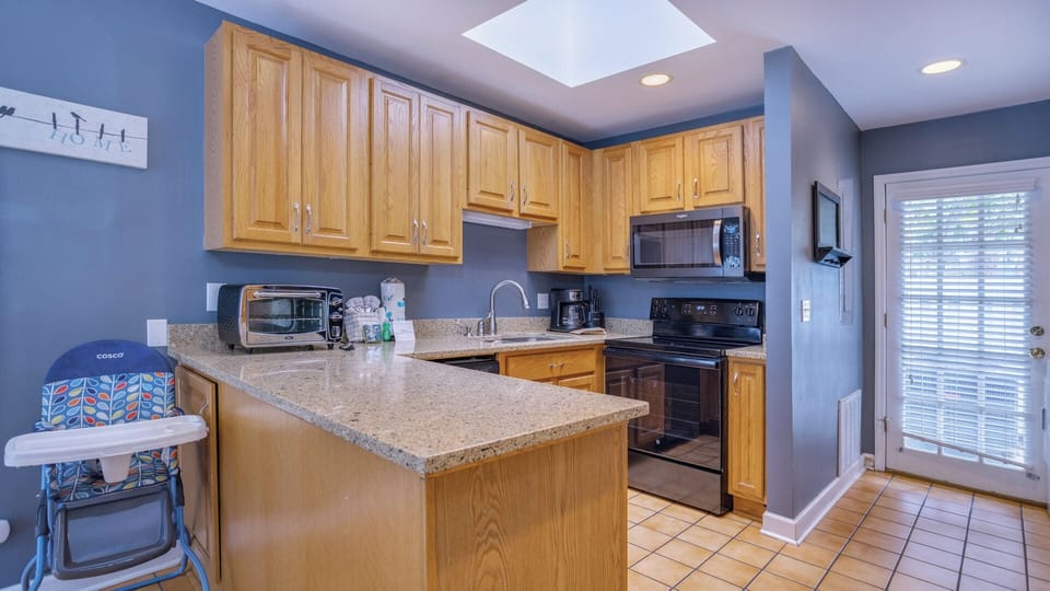 Stainless appliances, natural light from the skylight, and easy access to the outdoor living areas make this space both practical and welcoming.