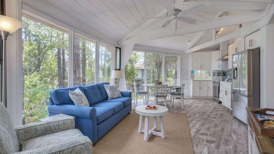 This bright and inviting sunroom offers a peaceful retreat surrounded by lush Lowcountry views.